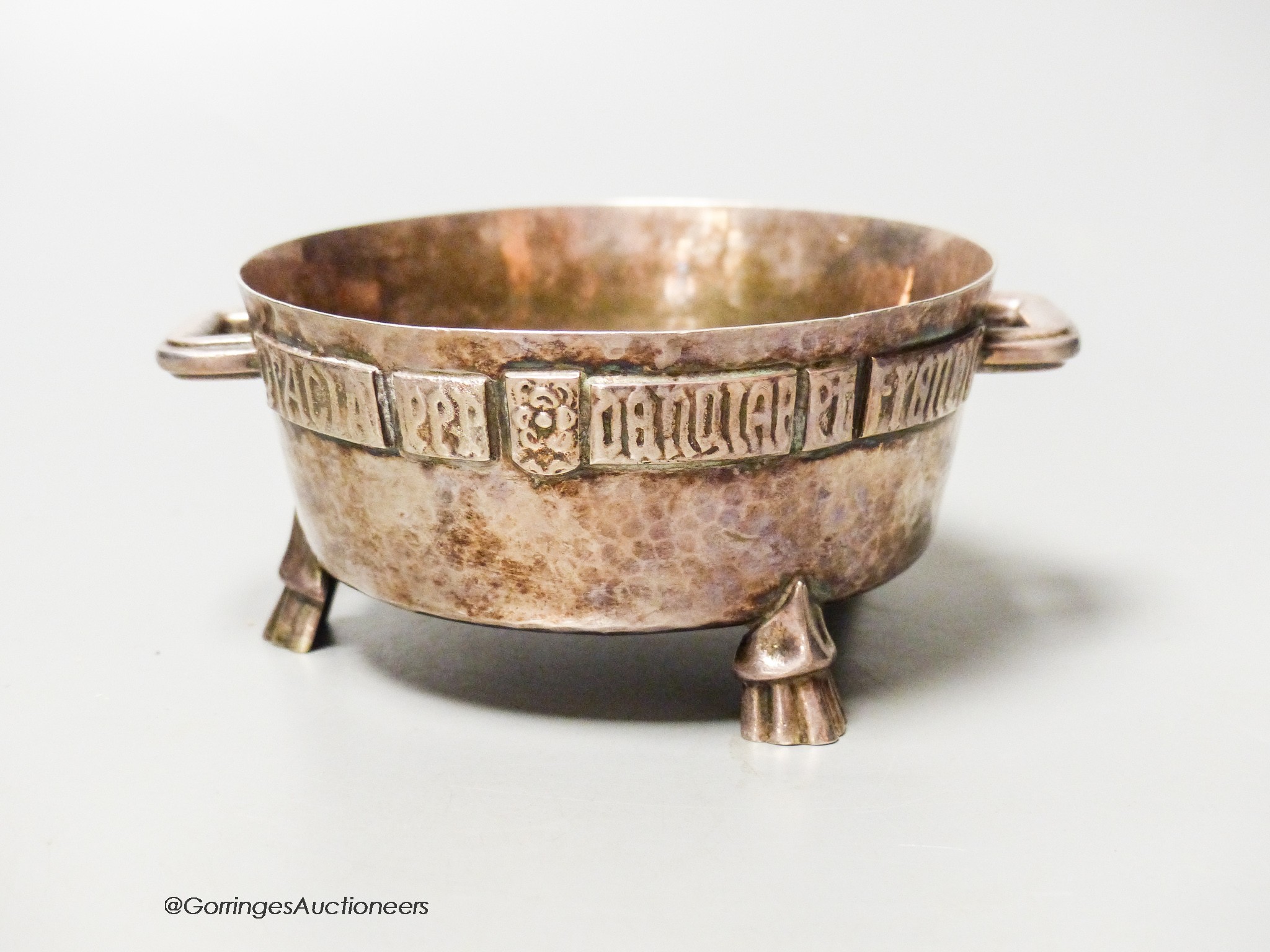 A George V Arts & Crafts planished silver twin-handled bowl, with applied Latin scripted border, F.J. Ross & Sons, London, 1923, diameter 10.5cm 7oz.